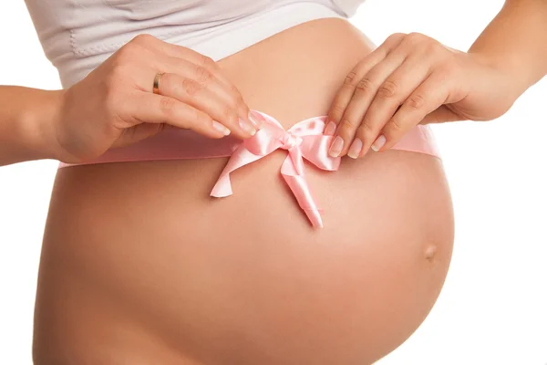 Ventre de femme enceinte avec ruban rose sur blanc — Photo