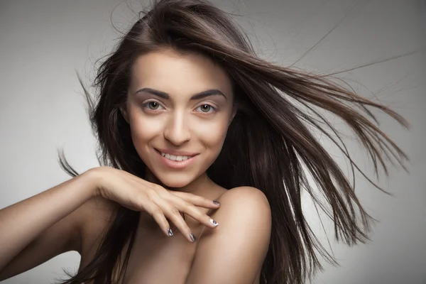 Attractive smiling woman with long hair on grey — Stock Photo, Image