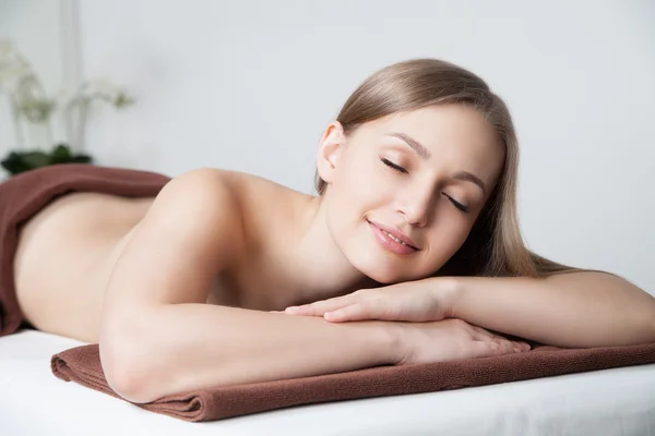 Frau im Wellness-Salon auf Massagetisch liegend — Stockfoto