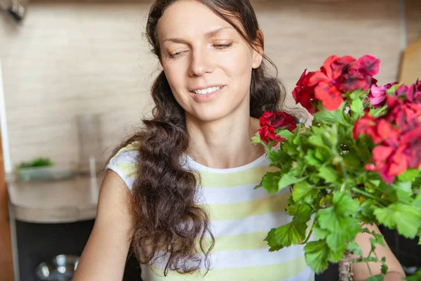 Mulher com flores jardinagem na cozinha em casa — Fotografia de Stock