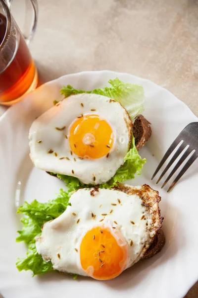 Pane tostato con uova fritte vicino a tè caldo Fotografia Stock