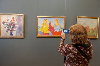 Saratov, Rusya. 13 Ekim 2021 'de Saratov Sanat Müzesi' nin Rus Sanat Salonu A.N. Radishchev. Müzeye gelen bir ziyaretçi resimlerin fotoğraflarını çeker.