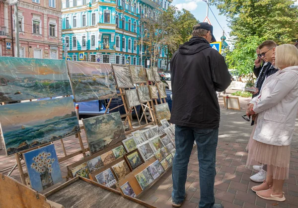 L'artiste à ses tableaux dans la rue et le public — Photo
