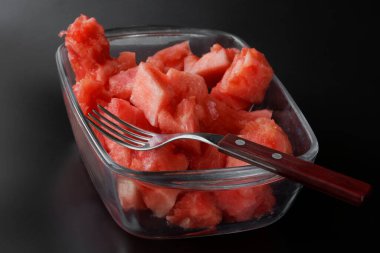 Çürümüş taze kırmızı karpuz parçaları şeffaf bir kasede. Siyah arka plan. Yakın plan.