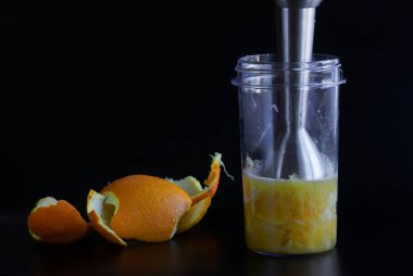 Portakal suyu ya da el blendırıyla püre yapmak. Siyah arka plan. Gün ışığı. Yakın plan.