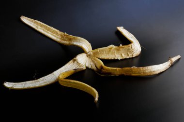 Koyu renk eğimli bir yüzeyde sarı muz kabuğu. Gün ışığı. Yakın plan.