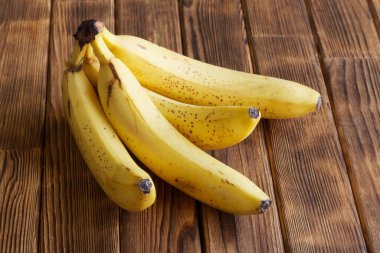 Olgun sarı muzlar ahşap tahtalardan yapılmış kırsal bir masada yatar. Yakın plan.