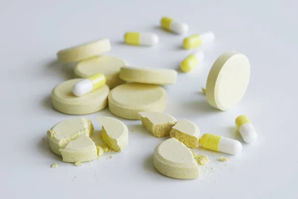 Κίτρινα Ιατρικά Χάπια Και Χάπια Ελαφρύ Φόντο Ολόκληρο Και Σπασμένο — Φωτογραφία Αρχείου