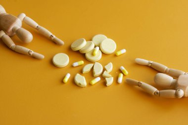 Two human dummies are drawn to a multitude of pills and pills. The concept of drug addiction, desire for recovery and drug shortages. Yellow background clipart