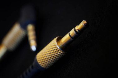 Analog ses sinyali için altın kaplamalı TRS konnektörleri siyah bir arkaplana karşı yerleştirilir. Küçük vale - 3.5 mm. İşitsel ekipman konsepti. Yüzeyin derinliği. Seçici odaklanma. Makro