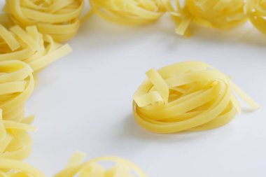 Durum buğdaylı fettucine makarna beyaz bir yüzeyde bulunur. Yemek pişirmek. Hafif arkaplan. Gün ışığı. Yakın plan.