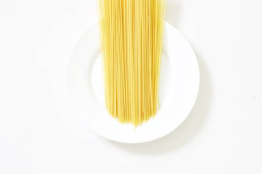 Hafif arkaplanda pişmemiş İtalyan spagettisi. Beyaz stili. Yukarıdan bak. Gün ışığı