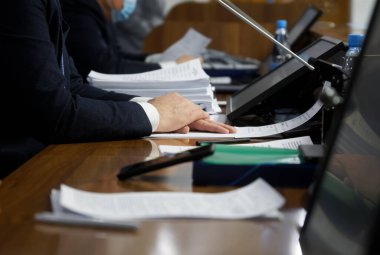 Adamların elleri - yetkililer, milletvekilleri, işadamları veya avukatlar, belgeler ve monitörlerle dolu bir masada oturuyorlar. Pazarlık, toplantı ya da konferans konsepti. Seçici odaklanma. Yüzü yok