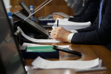 Önemli bir adamın elleri - bir politikacının, milletvekilinin, iş adamının ya da avukatın, belgeler ve monitörlerle dolu bir masada oturan. Pazarlık, toplantı ya da konferans konsepti. Seçici odaklanma. Yüzü yok