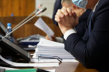 Erkeklerin elleri - yetkililer, avukatlar, milletvekilleri veya evraklar, mikrofonlar ve monitörlerle bir masada oturan iş adamları. Pazarlık, toplantı ya da konferans konsepti. Seçici odaklanma. Yüzü yok