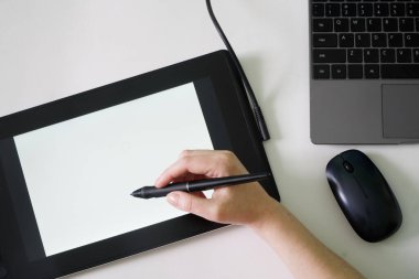 Kadının eli grafiksel tabletin ekranında dizüstü bilgisayarın yanında bir stil tutuyor. Beyaz arka plan. Modern yaratıcılık kavramı. Bir yazı için uzayı kopyala. Yakın plan.