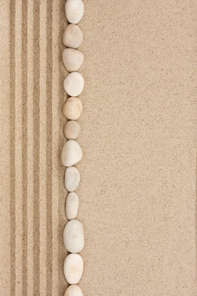 Bande de pierres blanches couchées sur le sable — Photo