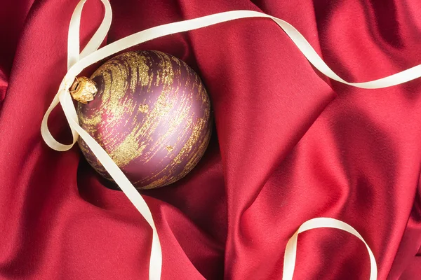 Рождественский бал лежал на красной ткани — стоковое фото