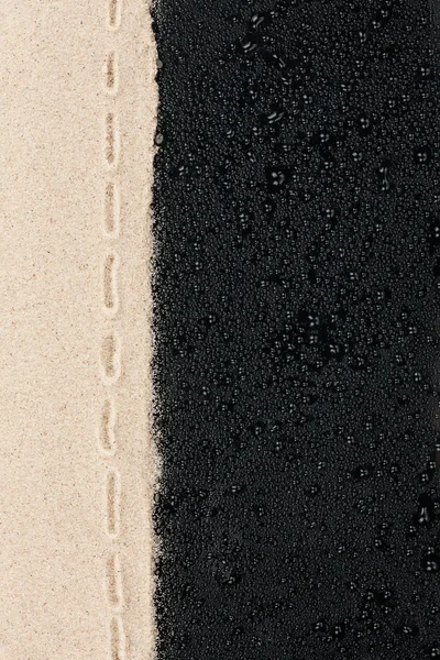 Zand op een zwarte achtergrond met waterdruppels — Stockfoto