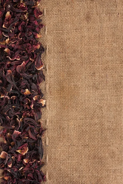 Dried hibiscus flowers petals lies on sackcloth — Stock Photo, Image