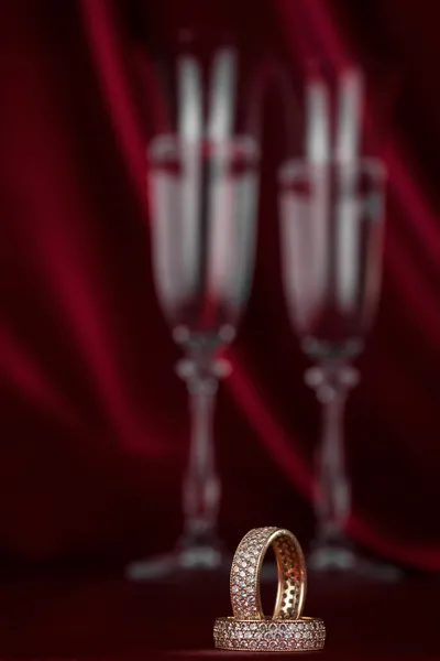 ワイングラスのペアの背景の上の結婚指輪 — ストック写真