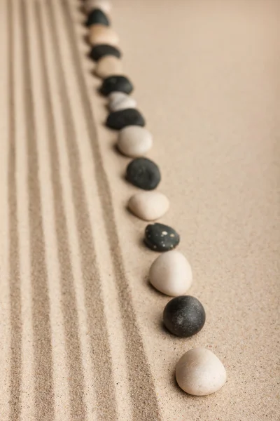 Stripe of white and black stones lying on the sand — Stock Photo, Image