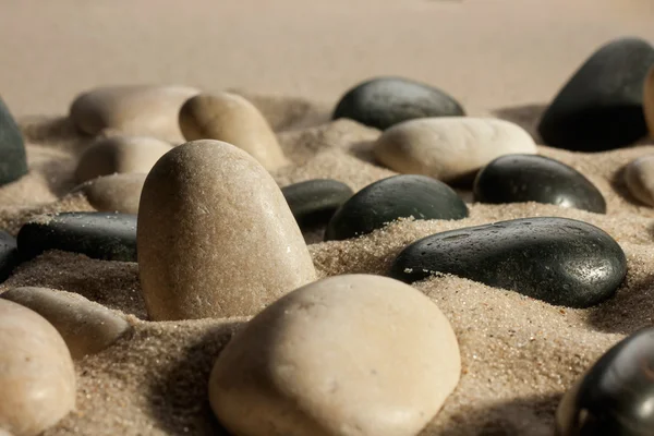 Closeup of stones sticking out of the sand in the sunlight — Stock Photo, Image