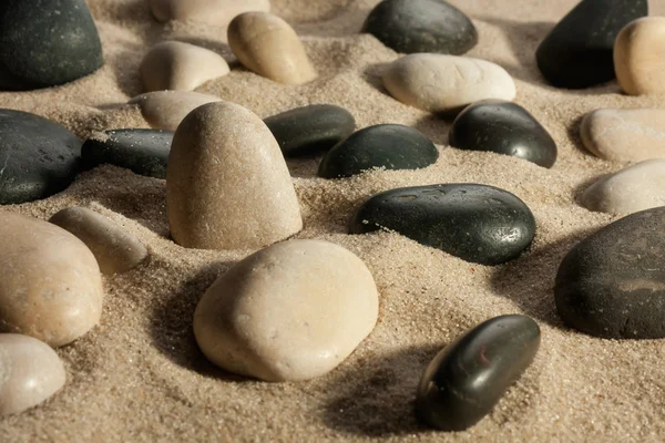 Closeup of stones sticking out of the sand in the sunlight — Stock Photo, Image