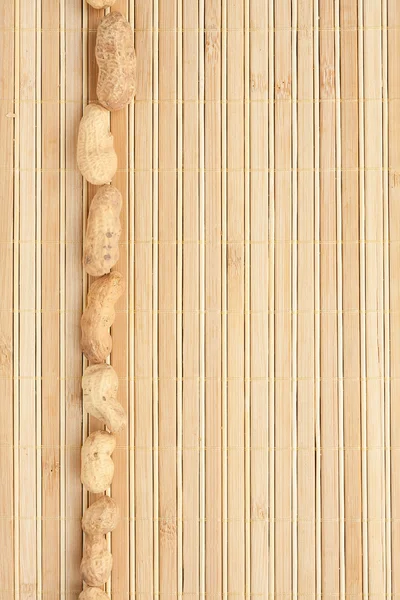 Casos una banda de cacahuete acostado en la estera de bambú —  Fotos de Stock