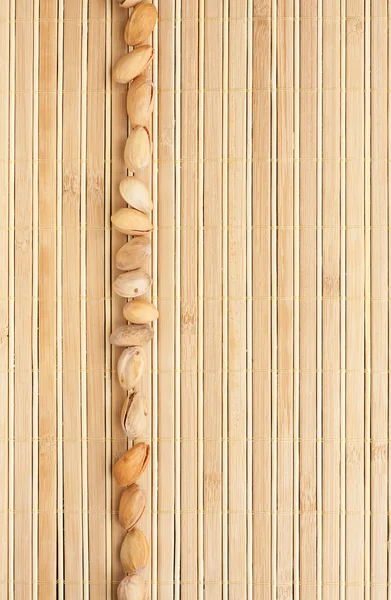 Cases a band of  pistachio  lying on bamboo mat — Stock Photo, Image