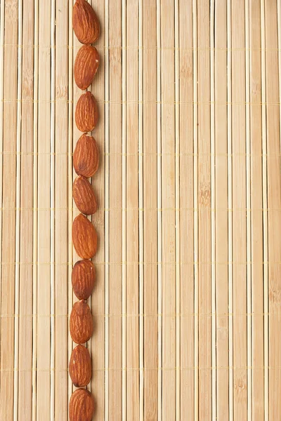 Cases a band of  almond  lying on bamboo mat — Stock Photo, Image