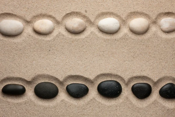 Piedras blancas y negras yaciendo en la arena — Foto de Stock