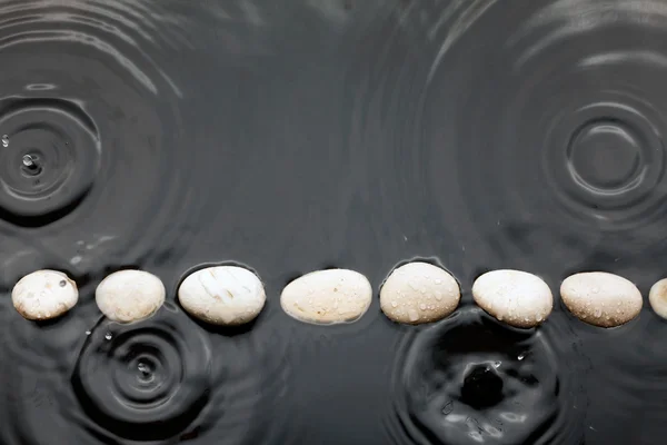 Pietre nere nell'acqua sotto la pioggia — Foto Stock