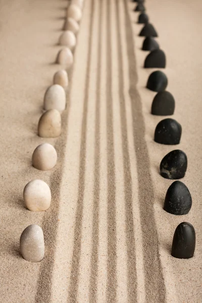 Stripe of white and black stones sticking of the sand — Stock Photo, Image
