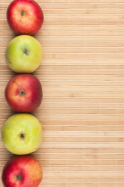 Green and red   apples lie on  bamboo mat — Stock Photo, Image