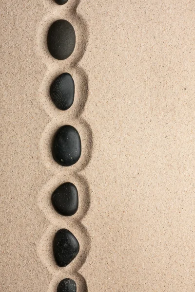 Line of black stones lying on the sand — Stock Photo, Image