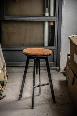 Bir ressam, kapalı beton bir zemine demir bir kütük bankı koyar.