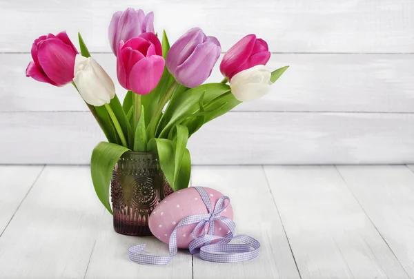 Tulipanes en un jarrón de cristal con huevo de Pascua — Foto de Stock