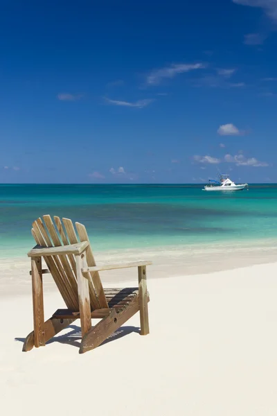 Silla de playa en la playa de arena con barco blanco en el fondo — Foto de Stock