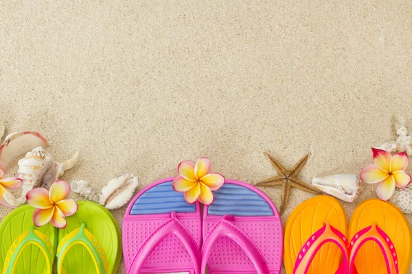 Chinelos na areia com conchas e flores de frangipani. Summe. — Fotografia de Stock