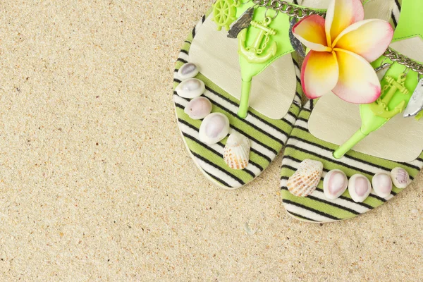 Сандалии, ракушки и франджипани на песке — стоковое фото