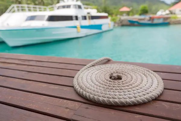 Rope folded in circle shape by the pier and speed boat on backgr — Stock Photo, Image