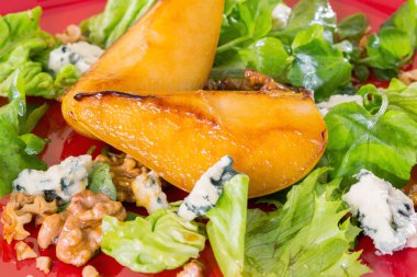 Salad with caramelised pears,walnuts and blue cheese, on red pla clipart
