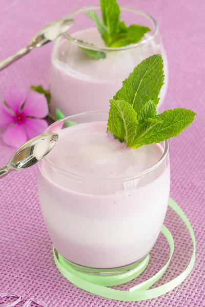 Due yogurt dessert su sfondo rosa, con cucchiaio, s nastro verde — Foto Stock
