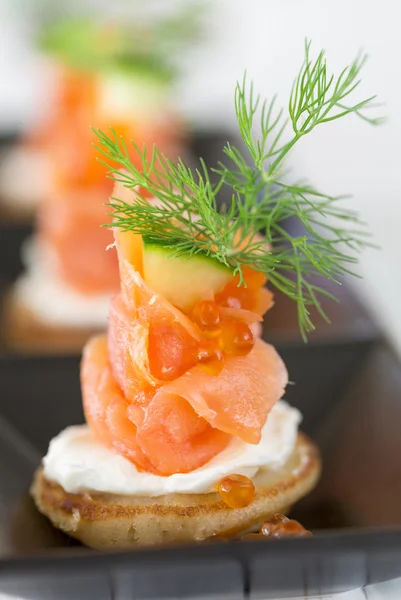 Blini met gerookte zalm en zure room, gegarneerd met dille — Stockfoto