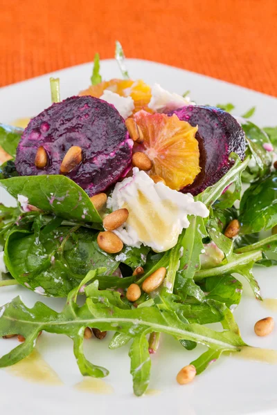 Verse salade met geroosterde rode biet, witte kaas, oranje en pine — Stockfoto