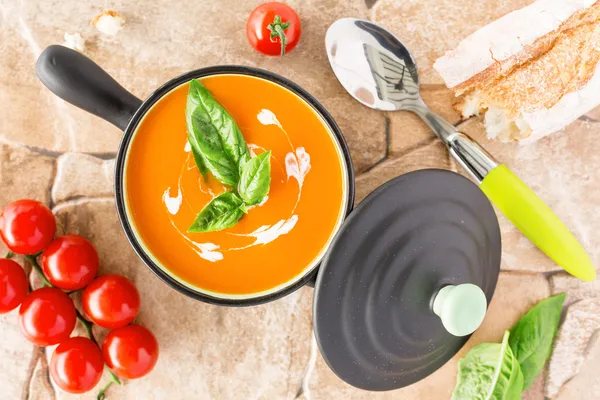 Tomato soup in a black casserole, drizzled with cream — Stock Photo, Image