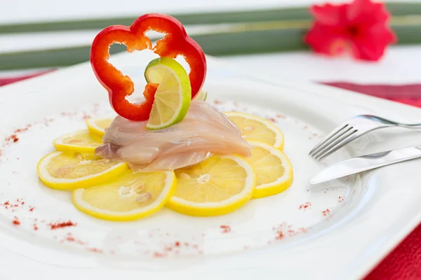 Carpaccio de pescado sobre limón, decorado con pimiento rojo rebanada a — Foto de Stock