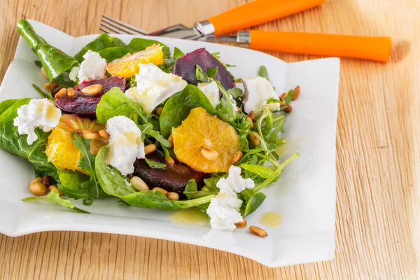 Tuore salaatti paahdetun punajuuren, valkoisen juuston, appelsiinin ja männyn kanssa — kuvapankkivalokuva