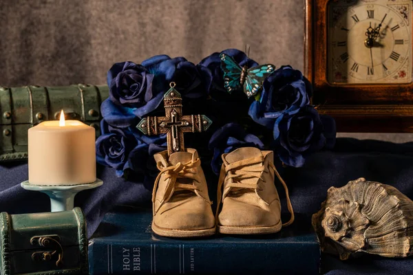 Still Life Old Baby Shoes Burning Candle Cross Blue Bible — Stockfoto